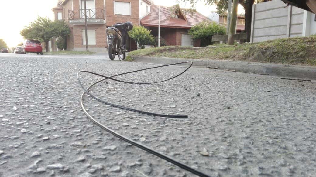 Un motociclista cayó sobre el asfalto al  enganchar un cable cruzado sobre la calle