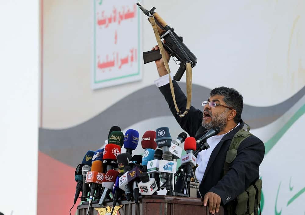 Mohammed Ali al-Houthi, miembro del consejo político supremo hutí, habla mientras sostiene un arma.