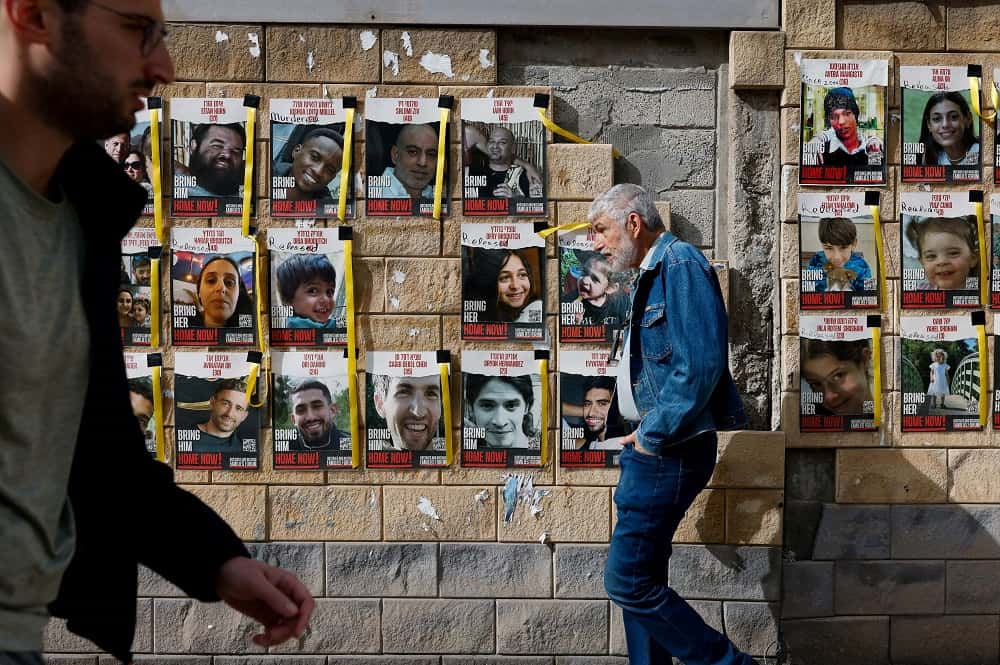 Varias personas caminan junto a pancartas con fotos de los rehenes secuestrados en el ataque del 7 de octubre de Hamás contra Israel.