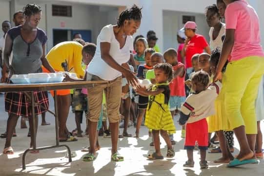 Niños haitianos reciben alimentos en una escuela de Puerto Príncipe que se utiliza como refugio.