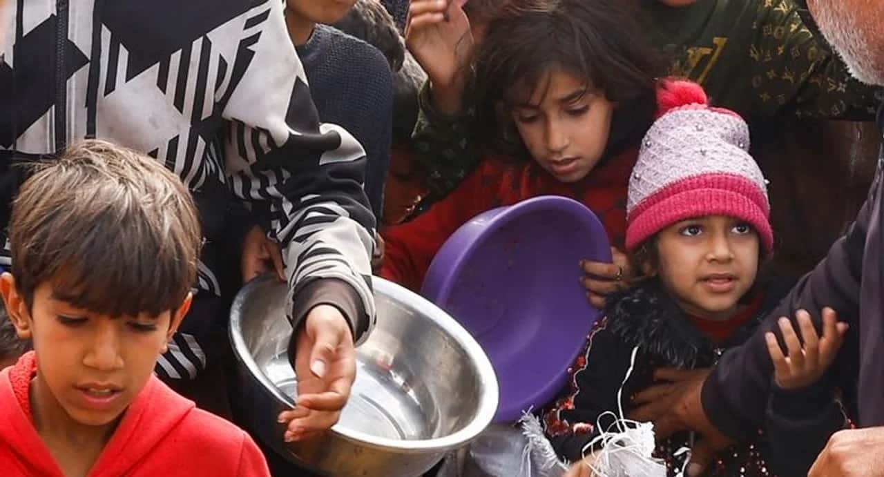 Niños palestinos esperan recibir alimentos.